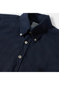 Camicia a maniche lunghe blu navy con colletto a punta, dotata di bottoni chiari e una sottile texture. Logo ricamato vicino all'orlo.