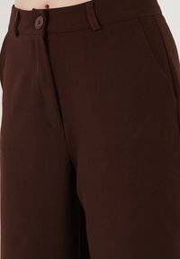 Braune maßgeschneiderte Hose mit einer glatten Textur, mit Knopfverschluss und Seitentaschen, entworfen mit geradem Bein und tailliertem Bund.