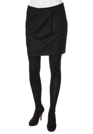 Jupe crayon noire en tissu à texture lisse, avec des plis sur le devant et une coupe ajustée. Portée avec des collants noirs et des talons hauts.