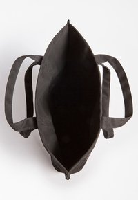 Sac fourre-tout en tissu noir avec deux poignées courtes et un dessus ouvert, doté d'un intérieur spacieux et d'une forme triangulaire. Aucun matériel ou motif visible.