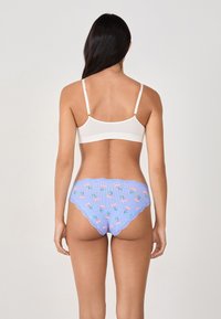 Soutien-gorge blanc à fines bretelles, accompagné de culottes à carreaux bleus avec des motifs de fleurs roses et une bordure en dentelle le long de la taille.