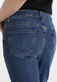 Blå denimjeans med hög midja, klassisk femfickdesign och kontrasterande sömmar, samt en mjuk och sl ät textur.