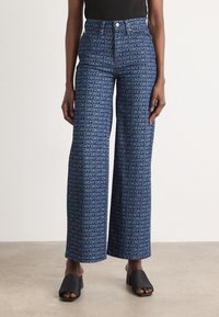 Weite Jeans in Blau mit einem umfassenden DKNY-Logo-Print. Denim-Material mit glatter Textur und hohem Bund.