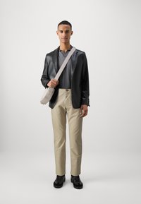 Black faux leather blazer, textured gray polo, beige trousers, black sneakers, and a light gray crossbody bag. Simple, modern design.