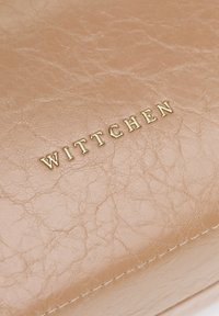 Rosa synthetische Lederhandtasche mit einer gerunzelt Textur und einem goldenen, eingeprägten "WITTCHEN"-Logo auf der Vorderseite. Die genähten Kanten sind sichtbar.