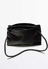 Borsa in pelle nera con texture liscia, caratterizzata da due scomparti con zip e una sottile tracolla curva.