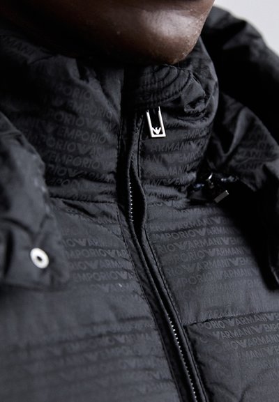 Crna puf jakna s teksturiranim završetkom i ponovljenim brendingom "Emporio Armani", zatvaračem i detaljima od srebrne boje.