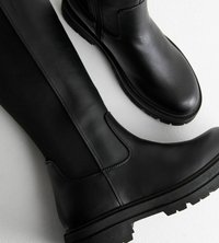 Botas de tobillo de cuero negro con una textura suave, con suela gruesa y acentos cosidos, diseñadas para la durabilidad y el estilo.