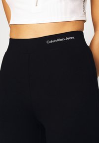 Zwarte legging van zachte stof met een hoge tailleband. Voorzien van het "Calvin Klein Jeans" logo in het wit bovenaan. Strak en aansluitend ontwerp.