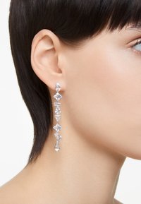 Kristallhängen i färger med växlande former: oval, diamant och päron, i silverfärgat metall, med en glänsande yta och en avlång design.