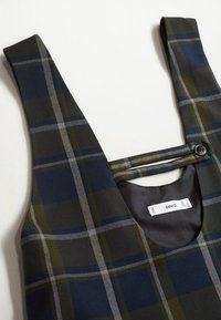 Robe sans manches à carreaux avec des rayures bleues, vertes et grises, avec une bretelle boutonnée sur l'encolure et une étiquette intérieure indiquant "MNG."
