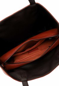 Sort læder tote bag indvendig med en orange lynlåslomme. Indeholder flere rum og en struktur af blødt læder.
