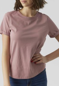 T-shirt met korte mouwen en ronde hals in licht mauve katoenmateriaal met een gladde textuur en een relaxte pasvorm, gecombineerd met blauwe jeans.