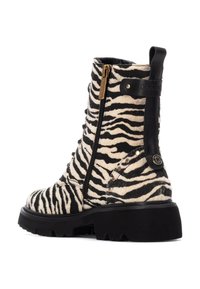 Botas hasta el tobillo con estampado de cebra, superiores de piel de textura de pelo, detalles de cuero negro, cremallera lateral y una suela negra gruesa con un diseño de tracción resistente.