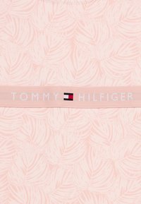 Ροζ υφασμάτινο με φυλλώδη σχεδίαση· διαθέτει λευκή ελαστική ταινία με τη σημείωση «TOMMY HILFIGER» και μικρό λογότυπο.