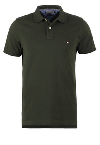 Tmavě zelené polo tričko vyrobené z bavlny s texturovaným povrchem, má límeček, zapínání na dva knoflíky a malé logo značky na hrudi.