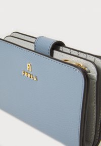Portefeuille en cuir bleu avec détail de logo doré, présentant une surface texturée et plusieurs compartiments, y compris une fermeture à pression sur le dessus.