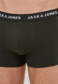 Dunkelgrüne Baumwollboxershorts mit einem figurbetonten Design, ausgestattet mit einem kontrastierenden elastischen Bund in Schwarz und Weiß mit dem Aufdruck "JACK & JONES" und einer glatten Textur.
