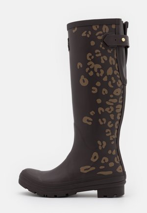 Botte de pluie noire haute avec des taches léopard marron et une sangle réglable près du haut sur fond blanc.