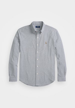 Long-sleeve button-up shirt in navy and white stripes. Features a classic collar, front buttons, and a small logo on the chest. Cotton blend.