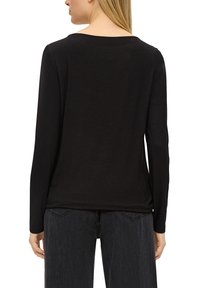 Czarny top z długim rękawem i okrągłym dekoltem, o miękkiej, gładkiej teksturze. Charakteryzuje się luźnym krojem i jest noszony z ciemnoszarymi dżinsami.