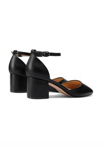 Scarpe in pelle nera con tacco a blocco e cinturino alla caviglia, design a punta, texture liscia e interno beige a contrasto.