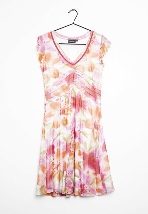Robe courte à fleurs avec des couleurs rose, orange et blanc, col en V, manches courtes et jupe plissée suspendue à un cintre noir.