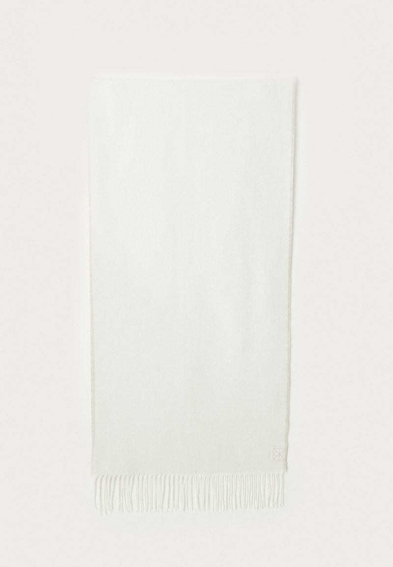 Hvit skjerf med frynser, laget av myk stoff. Har en subtil tekstur og en liten logo i et hjørne. Enkel design, rektangulær form.