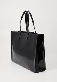 Saco tote preto feito de material brilhante, com duas alças longas e uma forma quadrada com arestas retas e um design sem emendas.