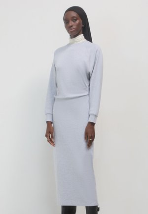 Vestito grigio chiaro a maniche lunghe in un tessuto morbido con una vestibilità rilassata, caratterizzato da un colletto alto e dettagli a coste. Texture liscia in tutto il capo.