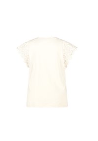 T-shirt à manches courtes de couleur crème avec des accents en dentelle festonnés sur les manches, fabriqué en coton doux, offrant une coupe décontractée.