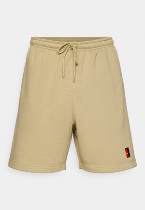 Shorts in cotone beige con vita elastica, cordoncino e un piccolo logo ricamato sulla gamba sinistra. Tessuto liscio e taglio lungo fino al ginocchio.