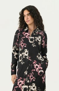 Rochie neagră din material floral, cu mâneci lungi, guler, modele abstracte în nuanțe de roz și alb, și buzunare laterale. Textură de material fin.