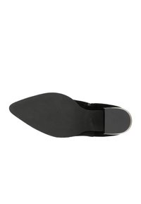 Chaussure noire en daim à bout pointu avec une semelle plate lisse et un petit accent près du talon. Le design est épuré et minimaliste.