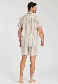 Mans kortärmad pyjamaset i krämfärg med blå ränder. Inkluderar en skjorta med krage och matchande shorts, tillverkade av mjukt och andningsbart tyg.