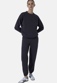 Donkergrijze sweatshirt en bijpassende joggers van zachte stof. De sweatshirt heeft een ronde halslijn; de joggers hebben elastische boorden en een casual pasvorm.
