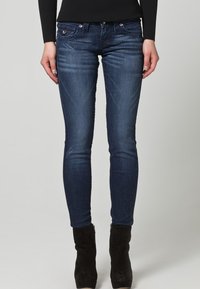 Mörkblå skinny jeans med en lätt blekning. Denimtyget har subtila slitningar vid låren. Femficksdesign med metallaccenter.