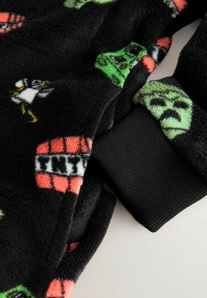 Schwarzer Fleece-Stoff mit bunten Cartoon-Motiven, darunter Figuren und Muster. Gerippter schwarzer Bund am Rand für zusätzlichen Detailreichtum.