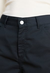 Black pants featuring a silver metal button closure, smooth fabric texture, and visible stitching along the seams. No pockets visible.