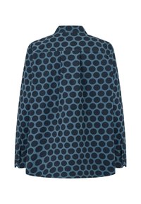 Camisetta a maniche lunghe di colore blu con pois blu scuro. Presenta un colletto a punta, polsini abbottonati e una piega sul retro per una maggiore forma.