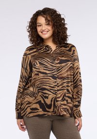 Camicia a righe marroni e nere con bottoni, colletto, maniche lunghe e vestibilità comoda. Tessuto: liscio, leggero.