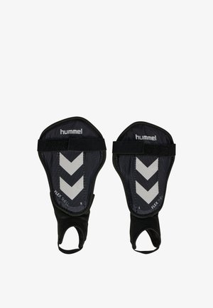 Sorte Hummel skinnebensbeskyttere med hvid chevron-design, elastiske stropper og fodsokker mærket højre og venstre, designet til fodboldbeskyttelse.