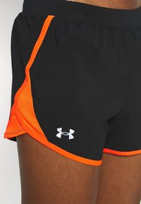 Pantalones cortos deportivos negros con acentos de malla naranja en los laterales, que cuentan con un logo de Under Armour blanco en la parte inferior izquierda. Tejido suave y ligero.