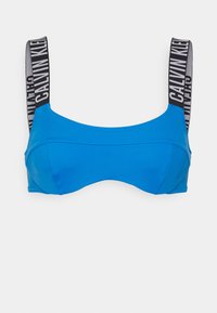 Blå BH med en jevn tekstur, med en strukturert design. Skulderstroppene er svarte med hvit "CALVIN KLEIN" merkevare.