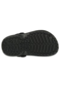 Semelle Crocs en caoutchouc noir avec un motif de grip texturé, un talon plus large et une forme arrondie. Logo visible au centre.