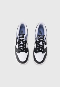 Mustavalkoiset Nike-tennarit, joissa on nahkainen ulkopinta, pyöreä kärki, rei'itetty kärkiosa ja mustat nauhat. Varustettu pehmustetulla kauluksella ja logokoristeilla.