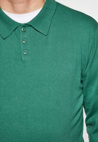 Groene polo shirt van gestructureerde stof met een klassieke kraag, een drie-knopen bediening en ribbeldetails.