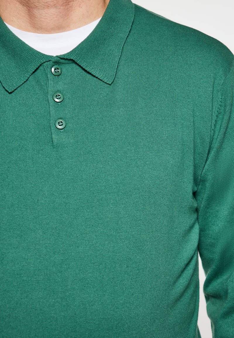 Groene polo shirt van gestructureerde stof met een klassieke kraag, een drie-knopen bediening en ribbeldetails.