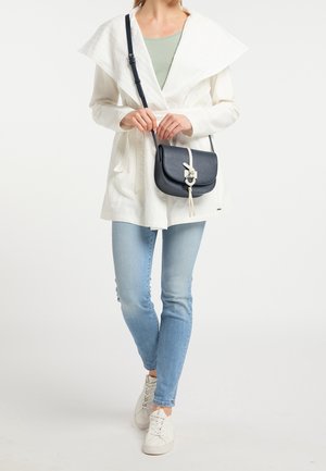 Hvid jakke med oversize krave, letvægtig stof, parret med lyseblå skinny jeans og en marineblå crossbody taske med en dekorativ lukning.