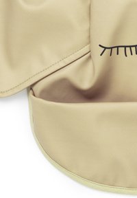 Tessuto liscio color beige con una leggera lucentezza, caratterizzato da un design a ciglia nere. I bordi sono rifiniti con un sottile profilo verde chiaro.